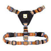 Colorful patterned dog harness with black chest pad and adjustable straps, featuring plastic buckles.