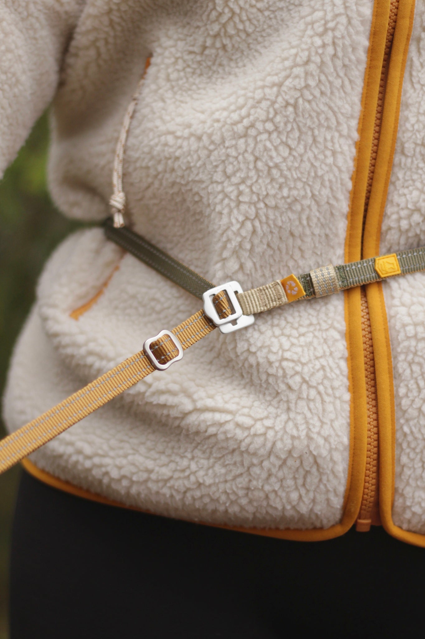 Person wearing a fleece jacket and a climbing harness clipped around their waist and leg.