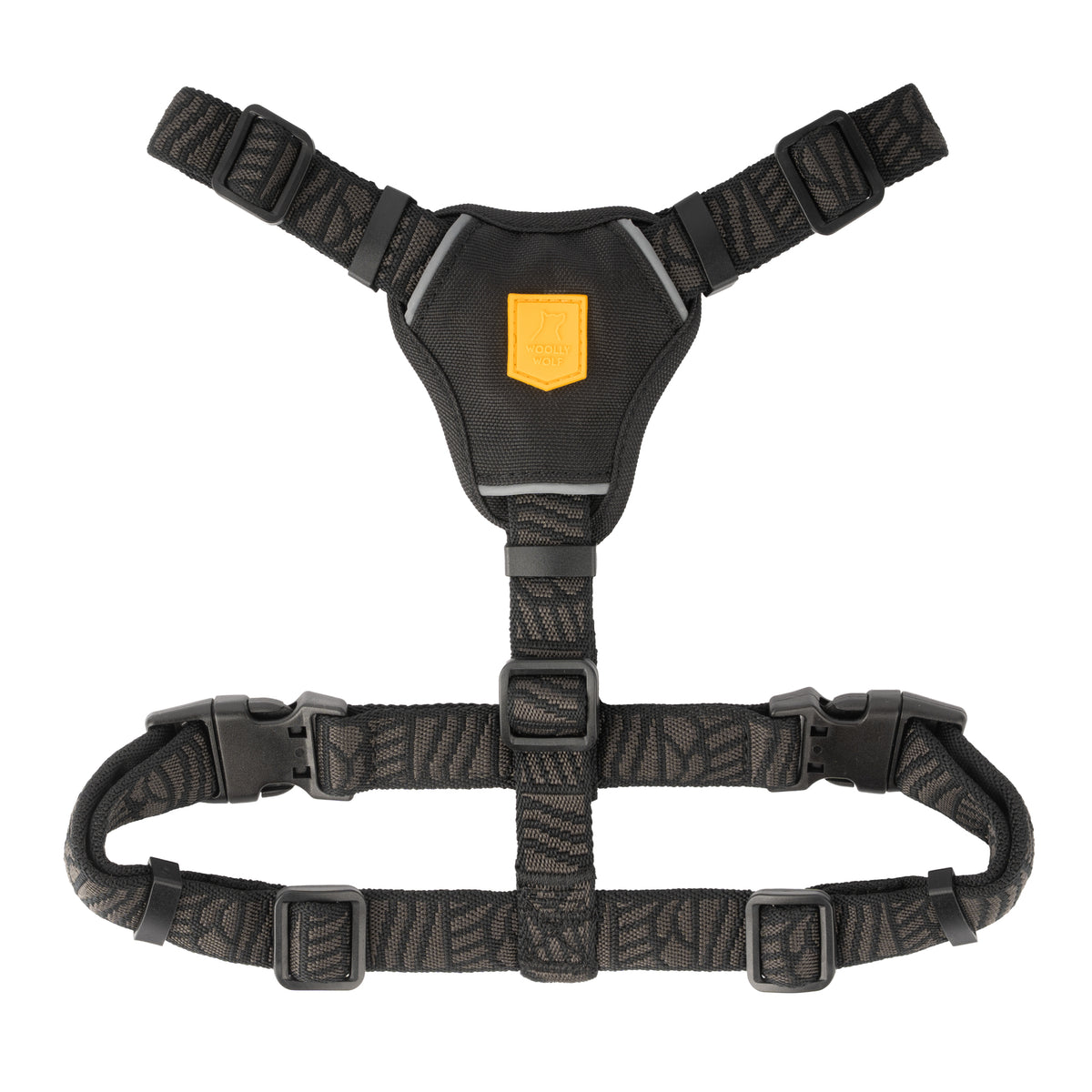 Black dog harness with a yellow logo patch and adjustable straps.